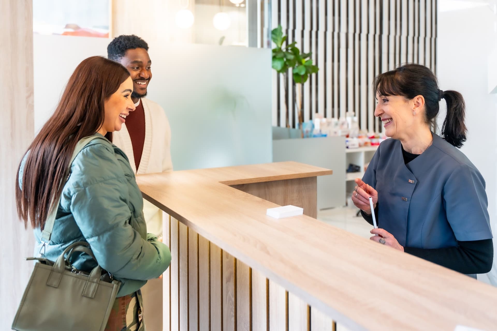 Dental team member smiling at the front desk of a modern practice